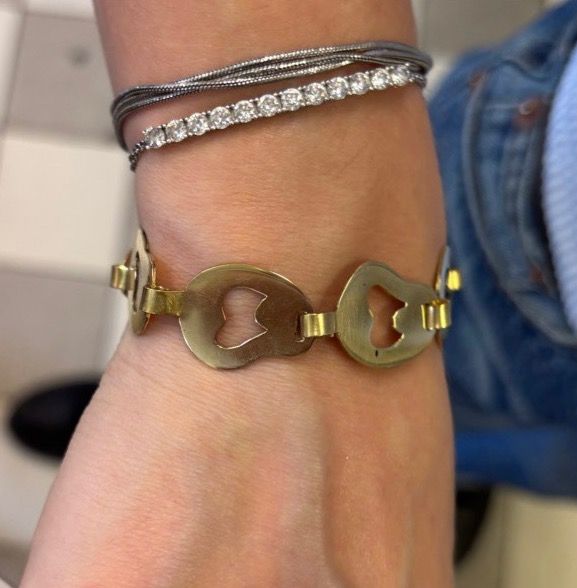 Bracelet porté au poignet, maillons ajourés visibles, à côté d'un bracelet de perles.