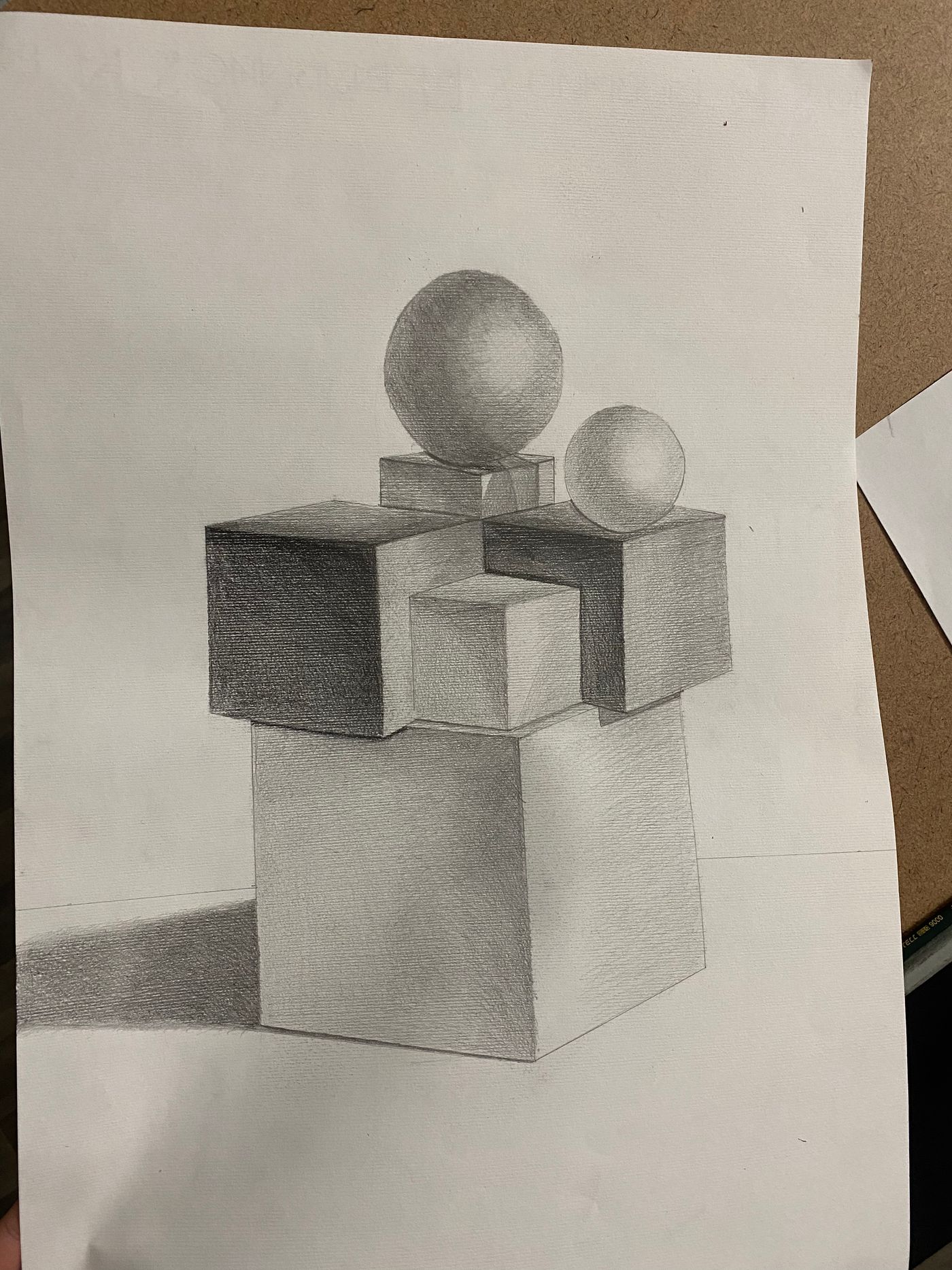 Dessin au crayon de solides géométriques empilés, cubes et sphères, avec ombre portée, feuille posée sur une table.