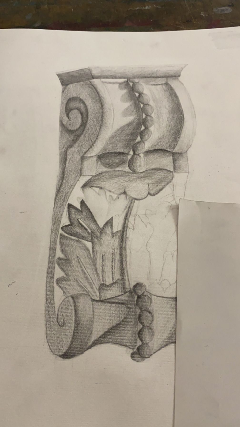 Dessin au crayon d'une console d'architecture à volutes et feuille d'acanthe, en partie recouvert d'une feuille de papier.